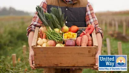 farmer holding wooden crate of fresh vegetables